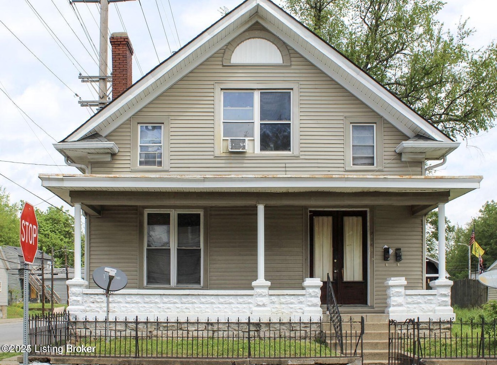 view of front of house featuring covered porch, a fenced front yard, a chimney, and cooling unit