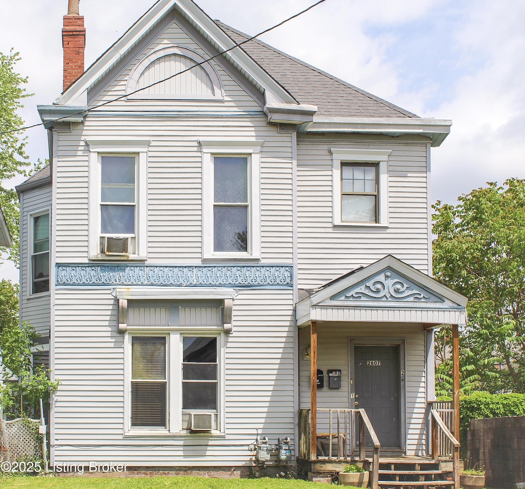 view of front of house featuring cooling unit, roof with shingles, and a chimney