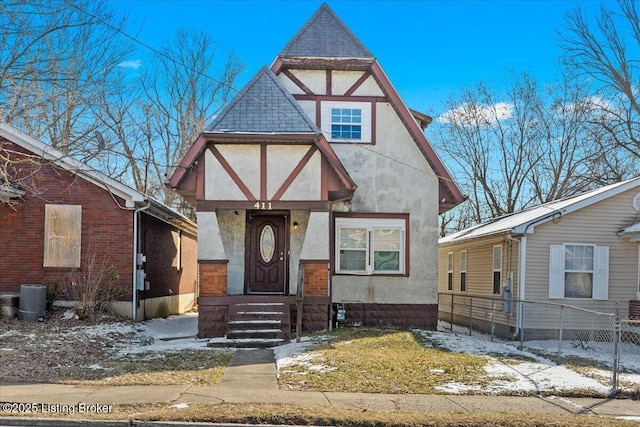 tudor-style house featuring fence and stucco siding