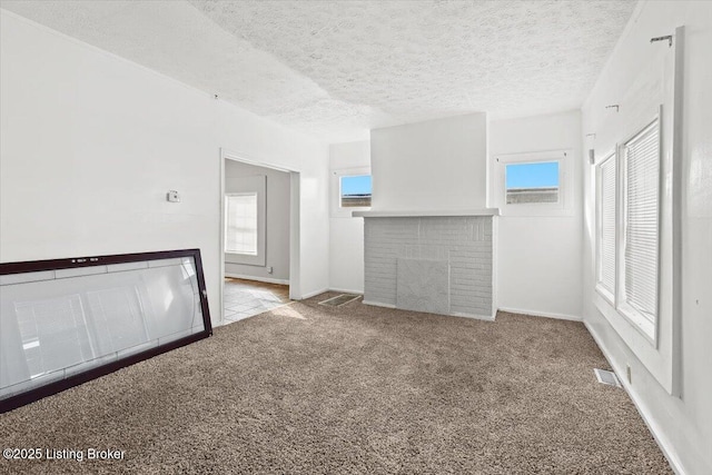 unfurnished living room with visible vents, a brick fireplace, light carpet, a textured ceiling, and baseboards