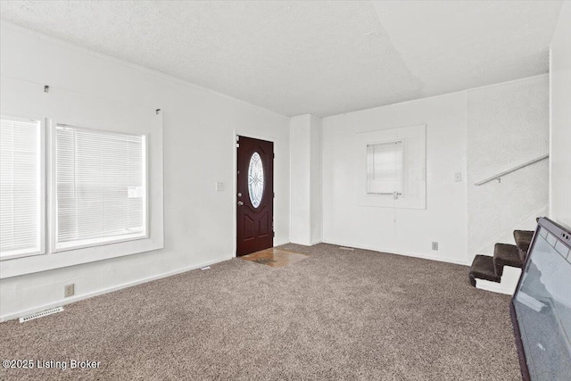 carpeted foyer entrance featuring stairway, visible vents, and a textured ceiling