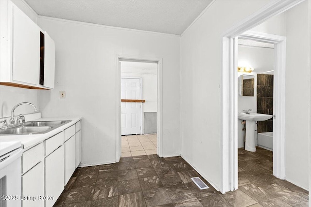 kitchen with a textured ceiling, a sink, visible vents, white cabinetry, and light countertops