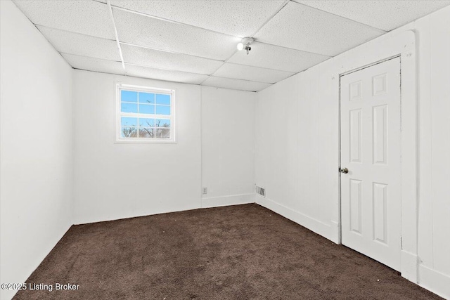 unfurnished room with a paneled ceiling and dark carpet