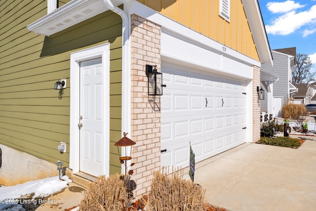 exterior space with a garage, concrete driveway, and brick siding