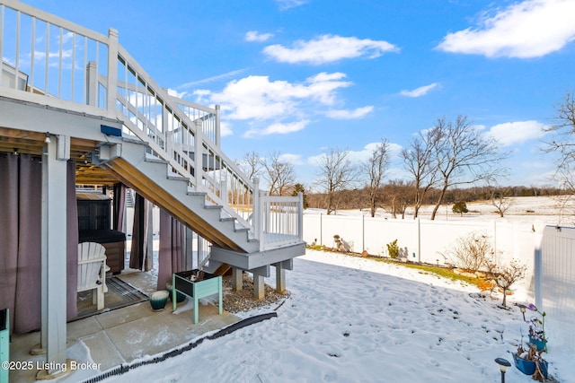 snowy yard with stairs and a fenced backyard