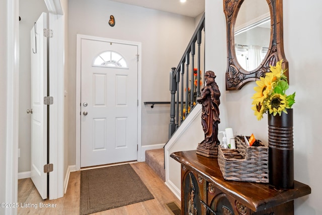 entrance foyer featuring light wood finished floors, baseboards, visible vents, and stairway