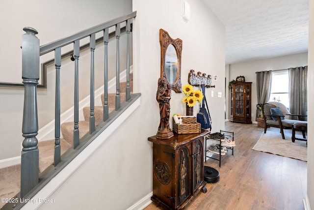 hallway with stairs, baseboards, and wood finished floors