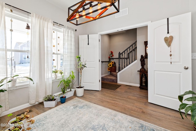 foyer with visible vents, stairway, baseboards, and wood finished floors