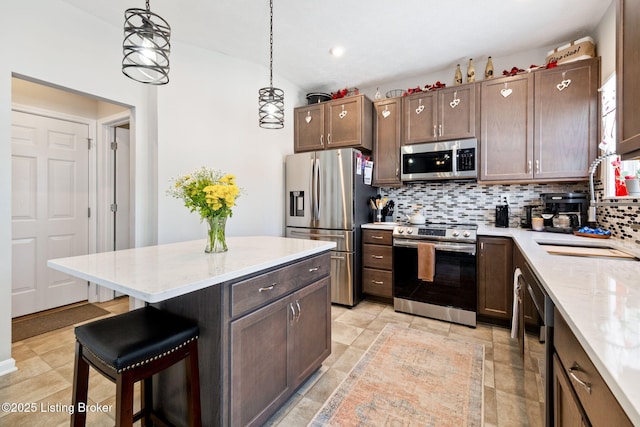 kitchen featuring decorative light fixtures, stainless steel appliances, decorative backsplash, dark brown cabinets, and a kitchen bar