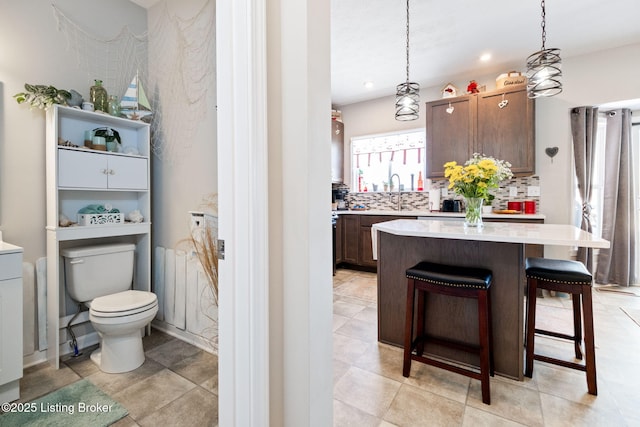 bathroom featuring toilet, tasteful backsplash, a sink, and recessed lighting