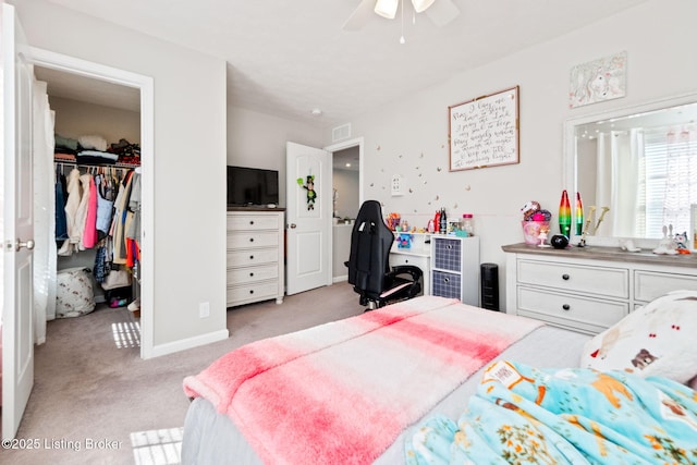 bedroom with a closet, light colored carpet, visible vents, a spacious closet, and a ceiling fan