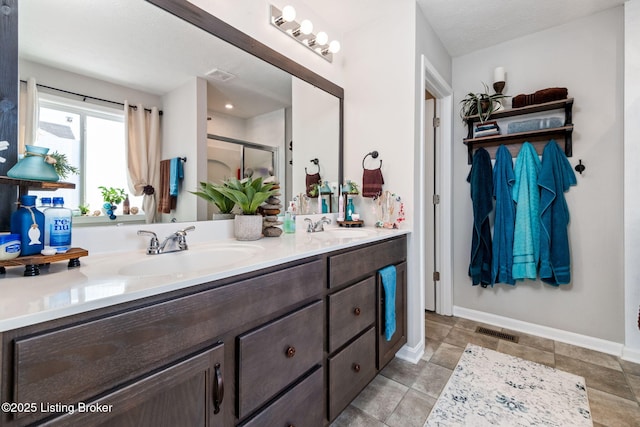 bathroom with double vanity, a sink, visible vents, and baseboards