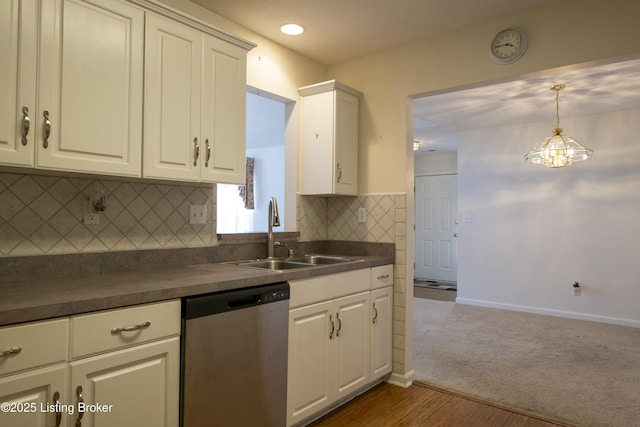 kitchen with stainless steel dishwasher, dark countertops, a sink, and decorative backsplash