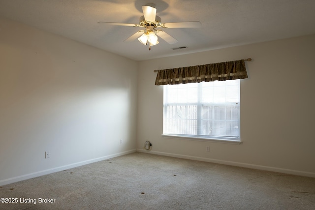 carpeted spare room featuring baseboards, visible vents, and ceiling fan