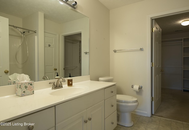 bathroom featuring a closet, toilet, vanity, baseboards, and walk in shower