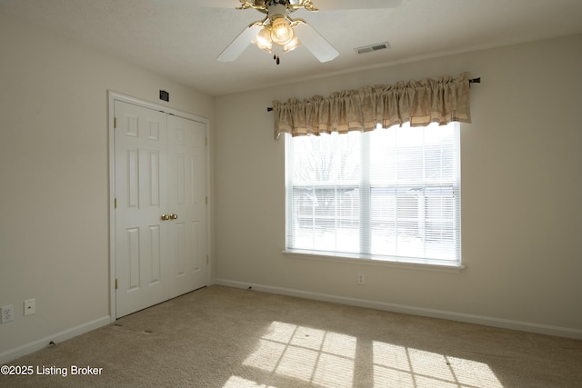 unfurnished bedroom with carpet floors, a closet, visible vents, a ceiling fan, and baseboards