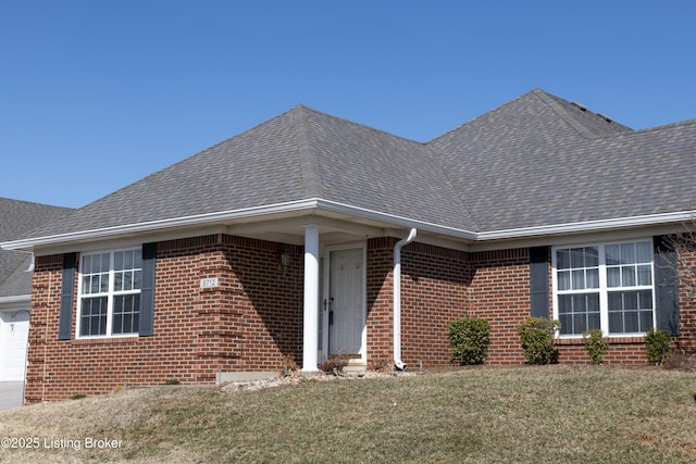 view of front of property featuring a garage, roof with shingles, a front lawn, and brick siding