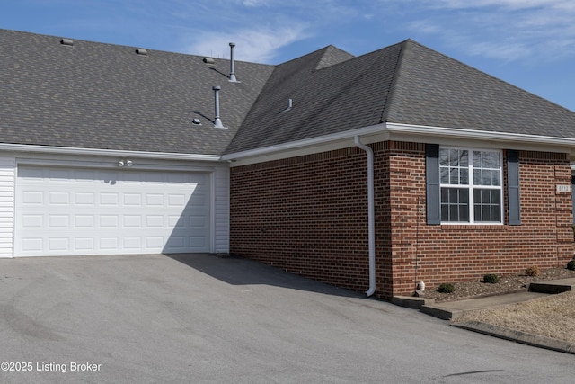 view of property exterior featuring an attached garage, roof with shingles, aphalt driveway, and brick siding