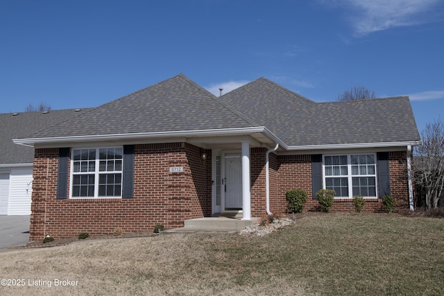 view of front of property featuring a shingled roof, a front yard, and brick siding