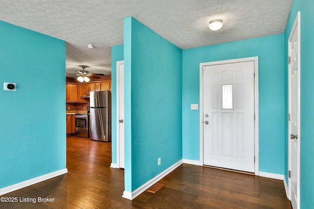 foyer entrance with dark wood-style flooring, a textured ceiling, and baseboards