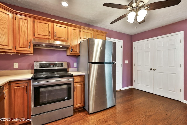 kitchen featuring stainless steel appliances, light countertops, under cabinet range hood, and dark wood-style floors