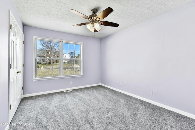 empty room featuring ceiling fan, carpet floors, a textured ceiling, and baseboards