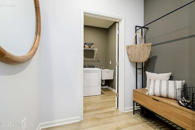 interior space featuring light wood finished floors, baseboards, washer / clothes dryer, and a sink