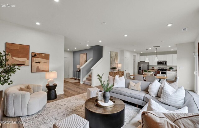 living area featuring stairs, light wood-type flooring, visible vents, and recessed lighting