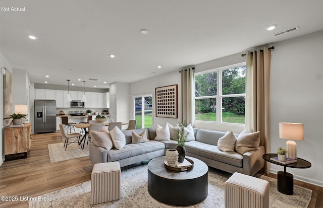 living room featuring recessed lighting, visible vents, light wood-style flooring, and baseboards