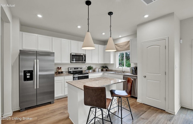 kitchen featuring light wood-type flooring, stainless steel appliances, a sink, and a center island