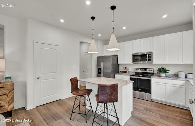 kitchen featuring a breakfast bar area, light wood finished floors, stainless steel appliances, recessed lighting, and a kitchen island