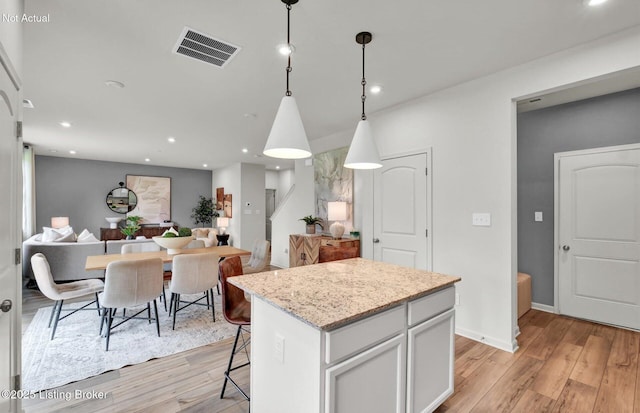 kitchen with light wood-type flooring, a center island, visible vents, and open floor plan