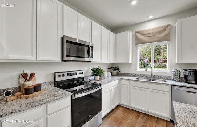 kitchen featuring light wood-style floors, white cabinetry, appliances with stainless steel finishes, and a sink