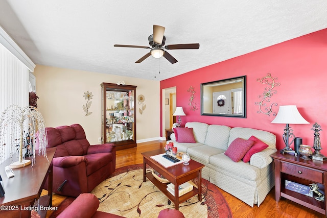 living area with a textured ceiling, ceiling fan, and wood finished floors