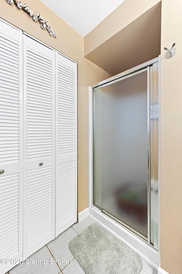 bathroom with a closet, tile patterned flooring, and a shower with shower door