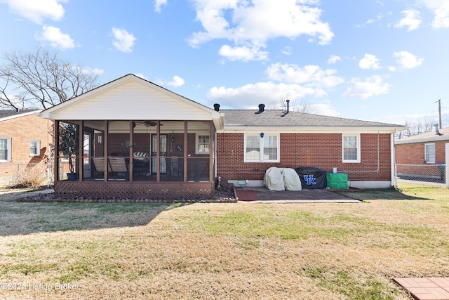 rear view of house featuring brick siding, a lawn, and a sunroom