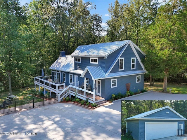 view of front of home with metal roof, a detached garage, fence, a wooden deck, and a chimney