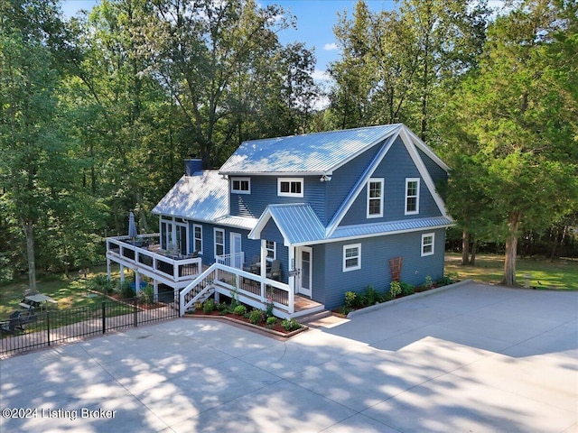 view of front of home with driveway, stairs, fence, and metal roof