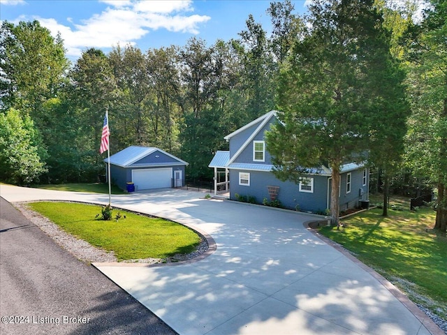 view of front facade with an outbuilding, concrete driveway, a detached garage, and a front yard