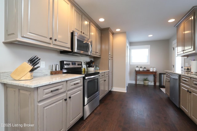 kitchen featuring recessed lighting, dark wood-style flooring, baseboards, appliances with stainless steel finishes, and light stone countertops