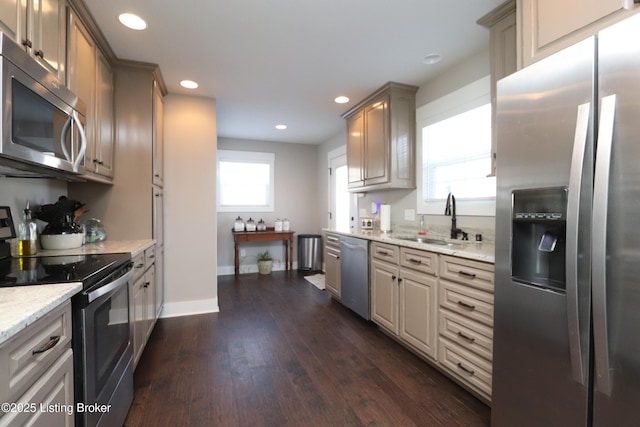 kitchen featuring dark wood finished floors, light stone countertops, stainless steel appliances, a sink, and recessed lighting