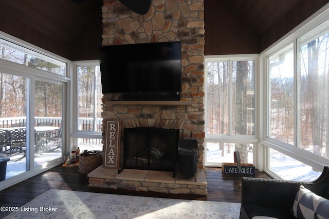 sunroom / solarium featuring lofted ceiling and a stone fireplace