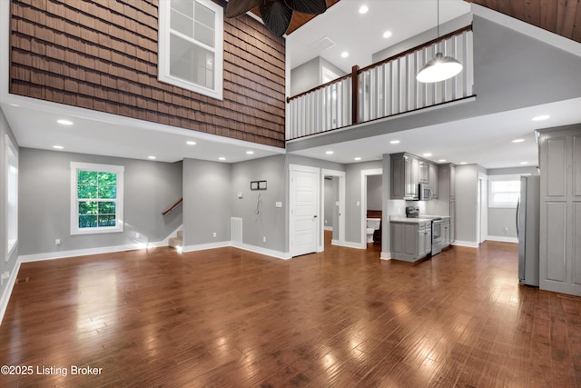 170 Moutardier Woods Way, Leitchfield, KY 42754 - unfurnished living room with a high ceiling, baseboards, stairs, and dark wood-style flooring