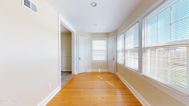 corridor featuring light wood-style flooring, visible vents, and baseboards