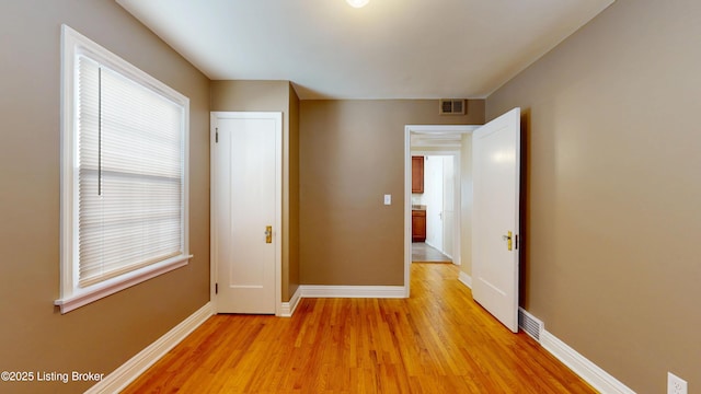 corridor featuring visible vents, light wood-style flooring, and baseboards