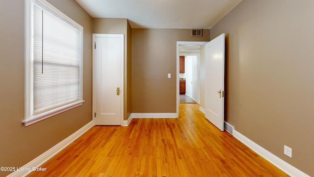 interior space with light wood-type flooring, visible vents, and baseboards