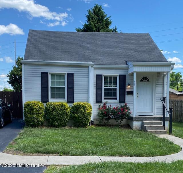 view of front of house featuring a front yard, roof with shingles, and fence