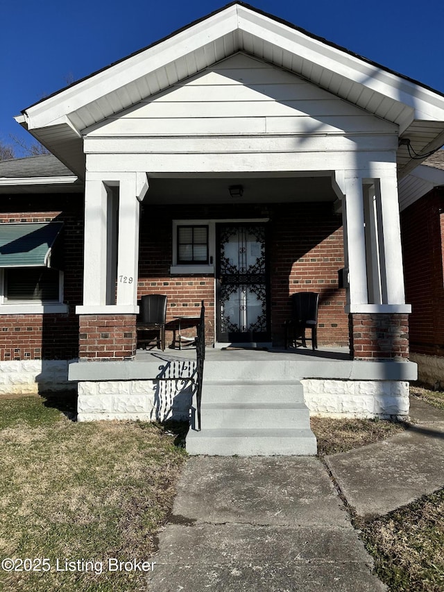 view of exterior entry with covered porch and brick siding