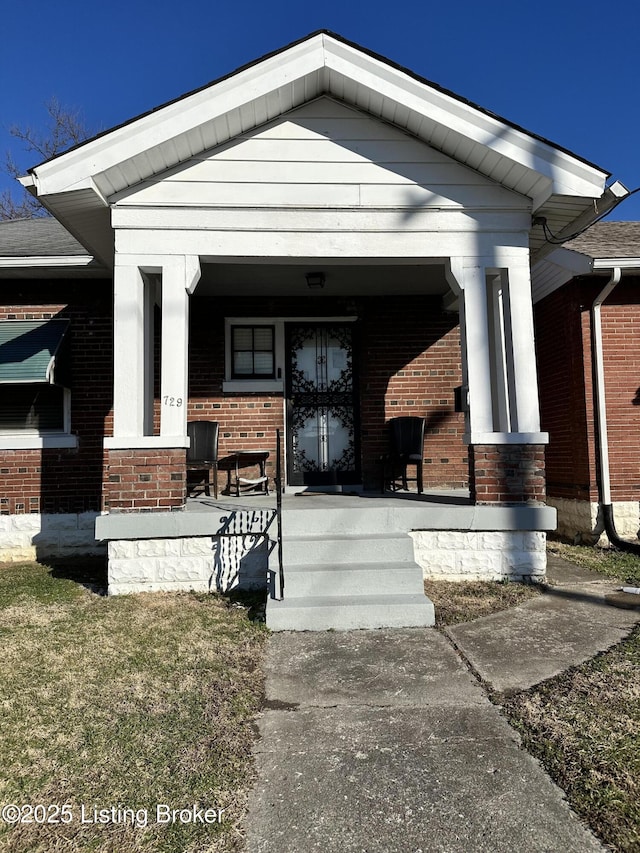 property entrance featuring covered porch and brick siding