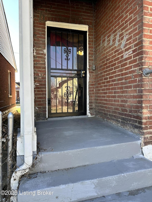 view of exterior entry featuring brick siding